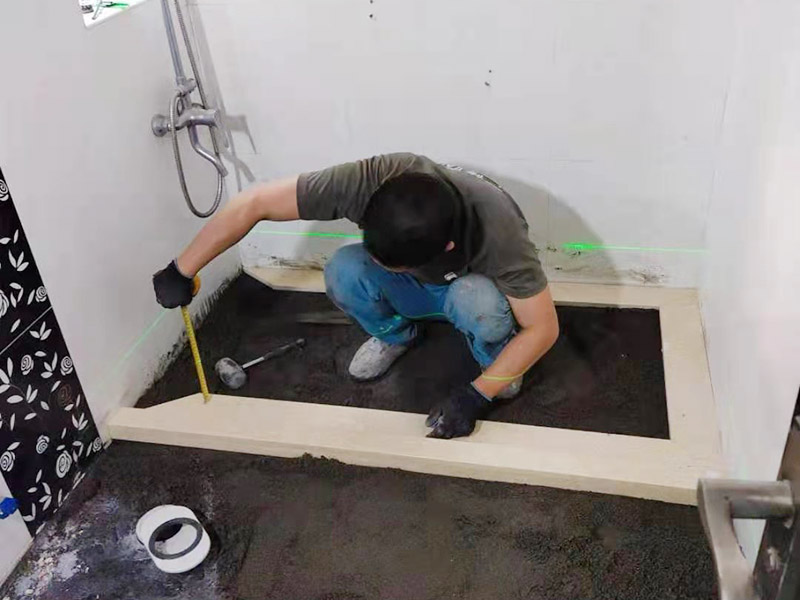 衛生間貼磚施工：應全部清理墻面上的各類污物，打掃干凈現場，特別是腳落里。用泥刀先批墻，后用水泥漿找平。這個工序很重要，確保底子平，防止貼后空鼓。墻面要刷防水涂料，防止貼后浸水，一般高度不低于1.8米，刷的時候會稍高一些。根據設計鋪貼圖樣的要求，確定排磚方案，用墨斗彈線，以減少施工損耗。用鋸齒鏝刀拉槽這點是目前新工藝區別老工藝的一點，使用將粘結劑漿料抹在待鋪貼基層表面，經由鋸齒鏝刀梳理后的條狀漿料飽滿并連續不間斷。瓷磚上墻將經過預先清潔的瓷磚平整地鋪貼在粘結劑漿料基層上，使用橡膠錘將瓷磚拍實鋪平。施工過程中，可小幅度轉動瓷磚，使漿料與瓷磚背面充分接觸。專家建議在鋪貼時，隨機取下已鋪貼于基層上的瓷磚作檢查。確保漿料與瓷磚背面的充分接觸。
